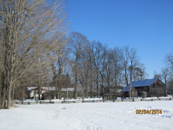 guest house in winter showing rail fence and outbuildings